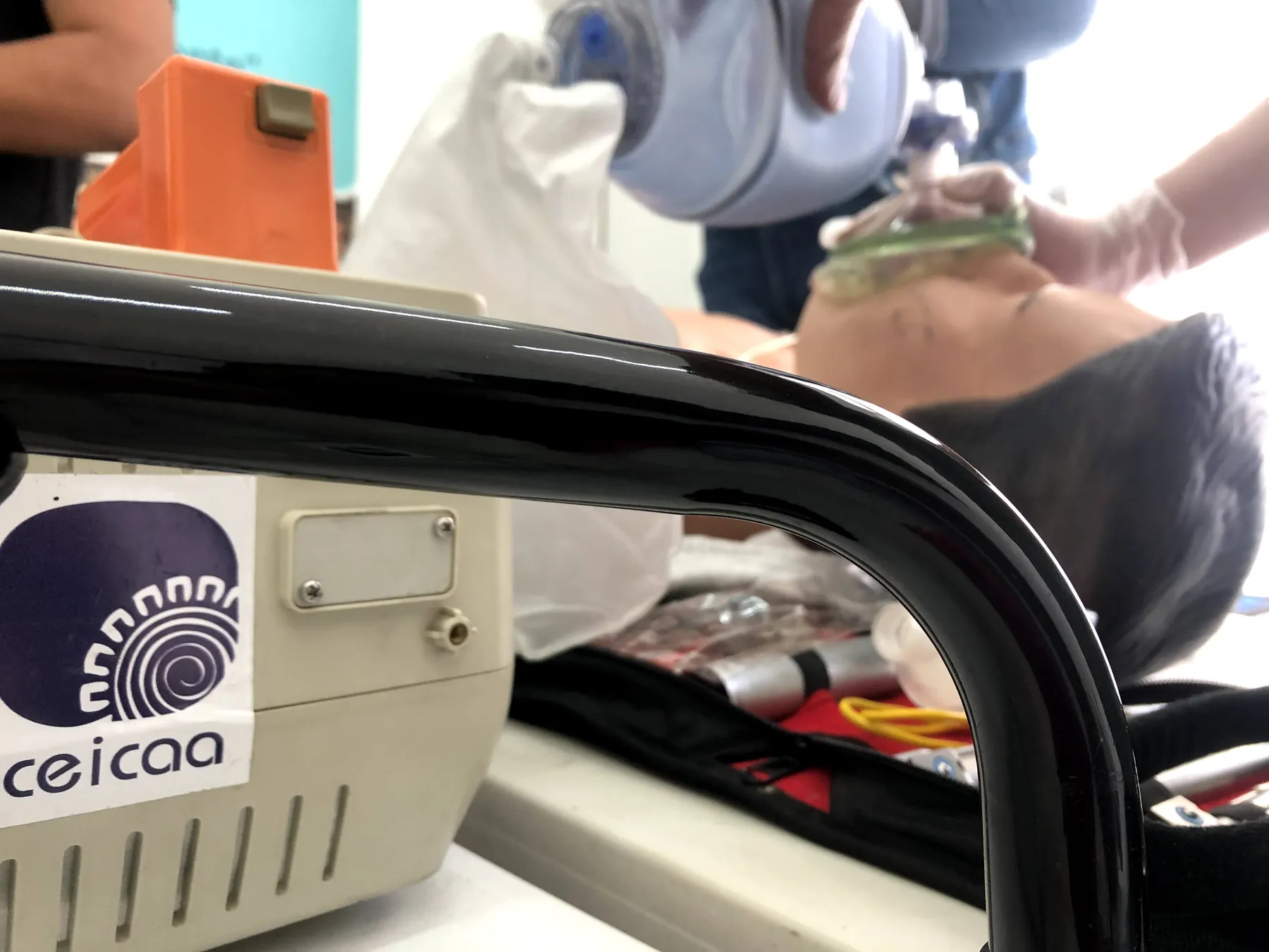 Ventilación con bolsa-válvula-mascarilla en un maniquí de ACLS; en primer plano, el monitor-desfibrilador con la etiqueta de CEICAA.